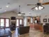 Spacious clubhouse interior featuring seating area, kitchen with bar, and ceiling fans at Embassy Ozark Apartments.