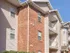 Exterior view of Embassy Ozark apartment building with red brick and beige siding, showcasing private balconies.