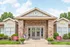 Front view of a welcoming building with a stone facade, featuring double glass doors and well-maintained landscaping. Signs indicate services.
