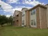 Two-story apartment building at Willow Creek Apartments in Springfield, MO, featuring tan siding and brick accents with a manicured lawn and mature trees.