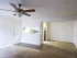 Spacious living room at Willow Creek Apartments with neutral carpet, ceiling fan, and a passthrough opening into the galley-style kitchen.