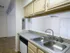 Bright galley kitchen at Willow Creek Apartments showcasing a double stainless steel sink, light cabinetry, and a view into the living area.