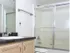 Detailed view of the bathroom at Willow Creek Apartments, highlighting the black countertop, under-sink storage, and glass shower doors.