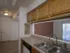 Compact kitchen at Willow Creek Apartments featuring wood cabinets, a double sink, and a passthrough window to the living area.