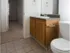 Simple bathroom with wood cabinetry, dark countertop, and tile flooring, located inside a unit at Willow Creek Apartments.