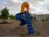 Outdoor playground at Willow Creek Apartments featuring a blue spiral slide and swing set, offering fun for families and children.