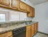 Renovated galley kitchen at Willow Creek Apartments showcasing granite-look countertops, wood cabinets, and a double sink with passthrough view.