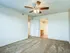 Bright bedroom with a ceiling fan, plush carpet, and a doorway leading into the private bathroom at Willow Creek Apartments.