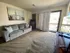 Living room with a cozy gray couch, artwork above, and a sliding glass door opening to a balcony. The room is carpeted and has a casual, homey atmosphere with decor that includes a sign reading 'HOPE.'