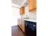 Simple galley-style kitchen with light wood cabinetry, white countertop, and black dishwasher&mdash;efficient and functional layout.