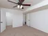 Spacious bedroom with neutral beige carpet, white walls, and a ceiling fan with a built-in light fixture. The room features an open doorway leading to a walk-in closet and another door opening to a hallway with dark wood flooring.
