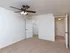 Bedroom with beige carpeting, a ceiling fan with a light fixture, and white walls. A walk-in closet is visible with an open door, and a hallway with multiple doors and a ceiling light is in the background.