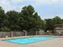 Peaceful pool area with concrete deck, privacy fence, and mature trees offering natural shade at English Village.
