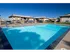 Sunny pool area with lounge chairs, stone pillars, and single-story brick buildings at English Village Apartments.