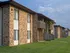 Side angle of English Village&rsquo;s brick apartment buildings with wood balconies and open grassy area.