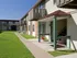 Ground-level patios and second-floor balconies along a sidewalk at English Village, with beige siding and green trim.