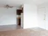 Open living area with a mix of carpet and tile flooring, ceiling fan, and partial view of kitchen cabinets and fridge.