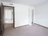 Spacious bedroom with small open closet, tan carpeting, and view into main hallway.