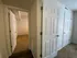 A hallway with white panel doors, one open to a carpeted room. Walls and doors are white, conveying a clean, neutral, and inviting atmosphere.