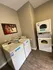 On-site laundry room at Cobblestone Village featuring commercial-grade washers and stacked dryers with wood-style flooring and wall art.