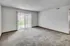 Carpeted living room with vertical blinds and sliding glass door leading to outdoor space.