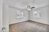 Corner bedroom with two windows, ceiling fan, and plush carpet at English Village Apartments.