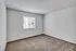 Simple bedroom with neutral carpeting and natural light from a single window.
