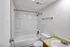 Bathroom with a full-size tub and shower combo, toilet, and single-sink vanity.