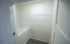 A walk-in closet featuring gray carpet, white walls, and a single wire shelf running the length of one wall.