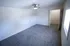 A large carpeted bedroom with a ceiling fan, white walls, and an open door leading to a walk-in closet with shelving.