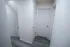 Interior hallway with three white panel doors and gray-toned wood flooring, located next to a stairwell with a visible wooden handrail.