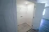 A small laundry closet with white walls, a single wire shelf, light fixture, and washer/dryer hookups on the back wall.