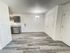Open dining space with chandelier lighting, double-door closet, gray vinyl plank flooring, and a partial view of the modern kitchen in the background.