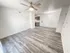 Open-concept living area with ceiling fan and view into the kitchen and dining space, featuring gray vinyl plank flooring and neutral walls.