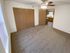 Carpeted bedroom with two large wooden closet doors, ceiling fan, and view into the adjoining kitchen area; window brings in natural light.