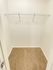 Empty walk-in closet with white walls, a beige carpet, and a white wire shelf across the top. The space appears clean and spacious.