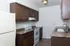 Galley-style kitchen with electric stove and dark wood cabinets at Timbers Apartments, ideal for efficient living near MSU.