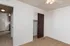 Bright, empty bedroom featuring beige carpet, white walls, a ceiling fan, and a closet with dark wood doors.