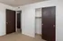 Interior of a vacant room featuring beige carpet, white walls, and dark brown closet doors. Two open doorways visible.