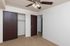 Bright, empty room featuring beige carpet, a ceiling fan, and two dark wood doors leading to a closet and hallway.