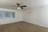 Living room with beige carpeting, white walls, a ceiling fan, and a front door next to a window with vertical blinds.