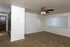 Spacious empty living room at Glen Isle/Cherry Lane Apartments featuring neutral carpeting, a ceiling fan with lights, and a large window with vertical blinds.