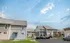 Suburban neighborhood with townhouses under a partly cloudy sky. Cars are parked in driveways, and a grassy lawn is visible, conveying a peaceful residential vibe.