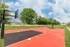 Wide view of the fenced outdoor court with trees in the background, offering a great amenity for active lifestyles.