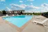 Corner view of the pool at Oak Court Apartments with modern apartment buildings and poolside loungers.
