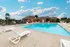 View of the Oak Court pool area with brick clubhouse and clear blue sky, surrounded by ample seating.