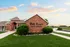 Brick entrance sign for Oak Court Luxury Apartments with manicured landscaping and sunset sky.