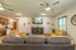 Clubhouse living room at Republic Palms Apartments styled with modern yellow and gray furniture, wall-mounted flat-screen TV, ceiling fans, and homey wall art, providing a comfortable space for residents to relax and socialize.