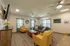 Spacious community lounge at Republic Palms Apartments in Republic, MO, featuring yellow armchairs, a gray sofa, and wood-style flooring beneath modern ceiling fans.