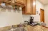 Compact clubhouse kitchen area featuring a stainless steel sink, wood cabinets, granite-look countertops, and a coffee station setup with mugs and supplies&mdash;ideal for resident events and gatherings.